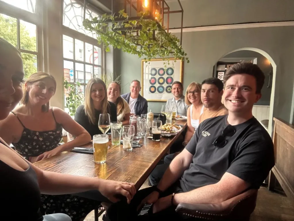 The Atkinson Moss team of eight is posing for a picture around a table.